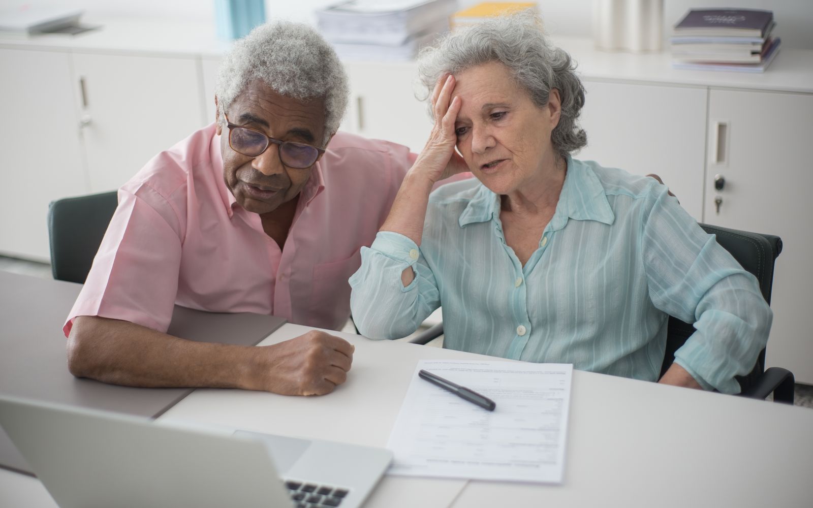 A couple reviewing documents and a laptop at their kitchen table