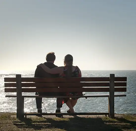 Two people sitting on a waterfront bench