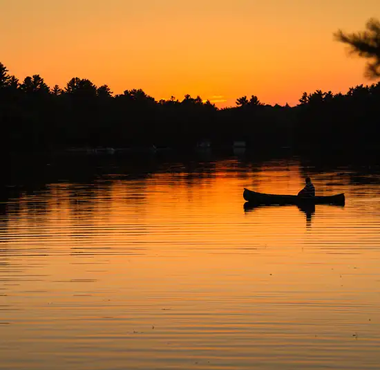 Canoe silhouetted on calm water at sunset